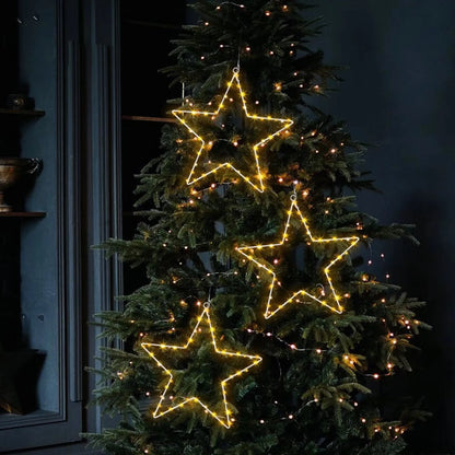 LED window stars glowing on an outdoor fir tree at night