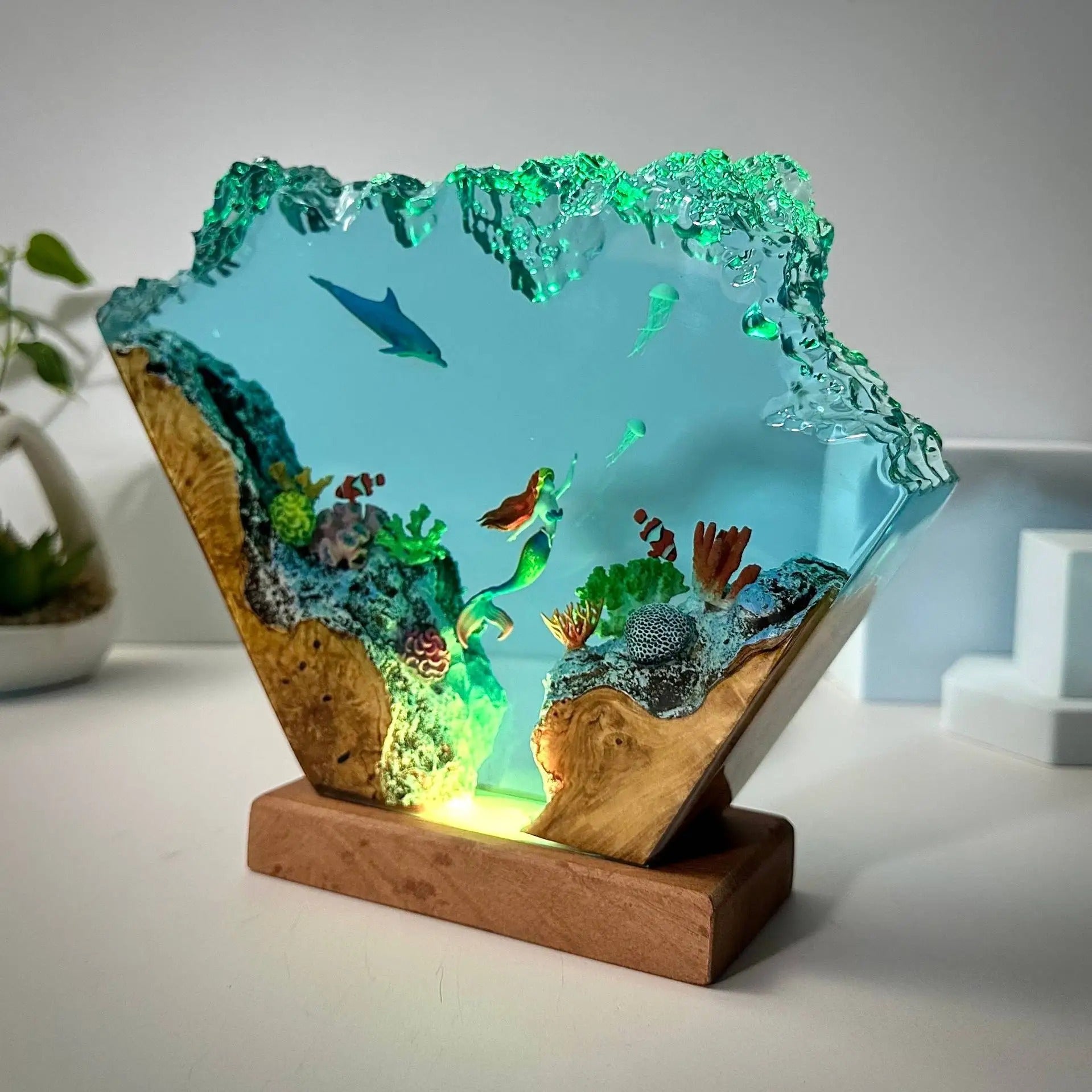 Dolphin and mermaid epoxy resin lamp glowing on a wooden base